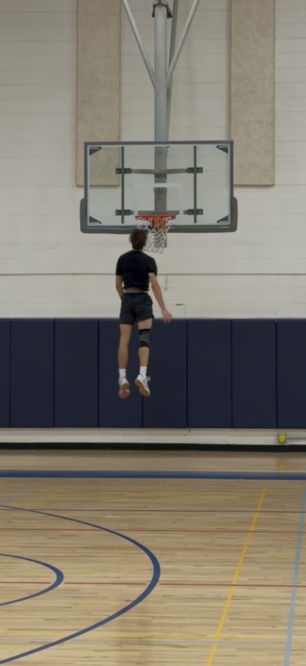 Jake in mid-air at the rim with a brace on his knee
